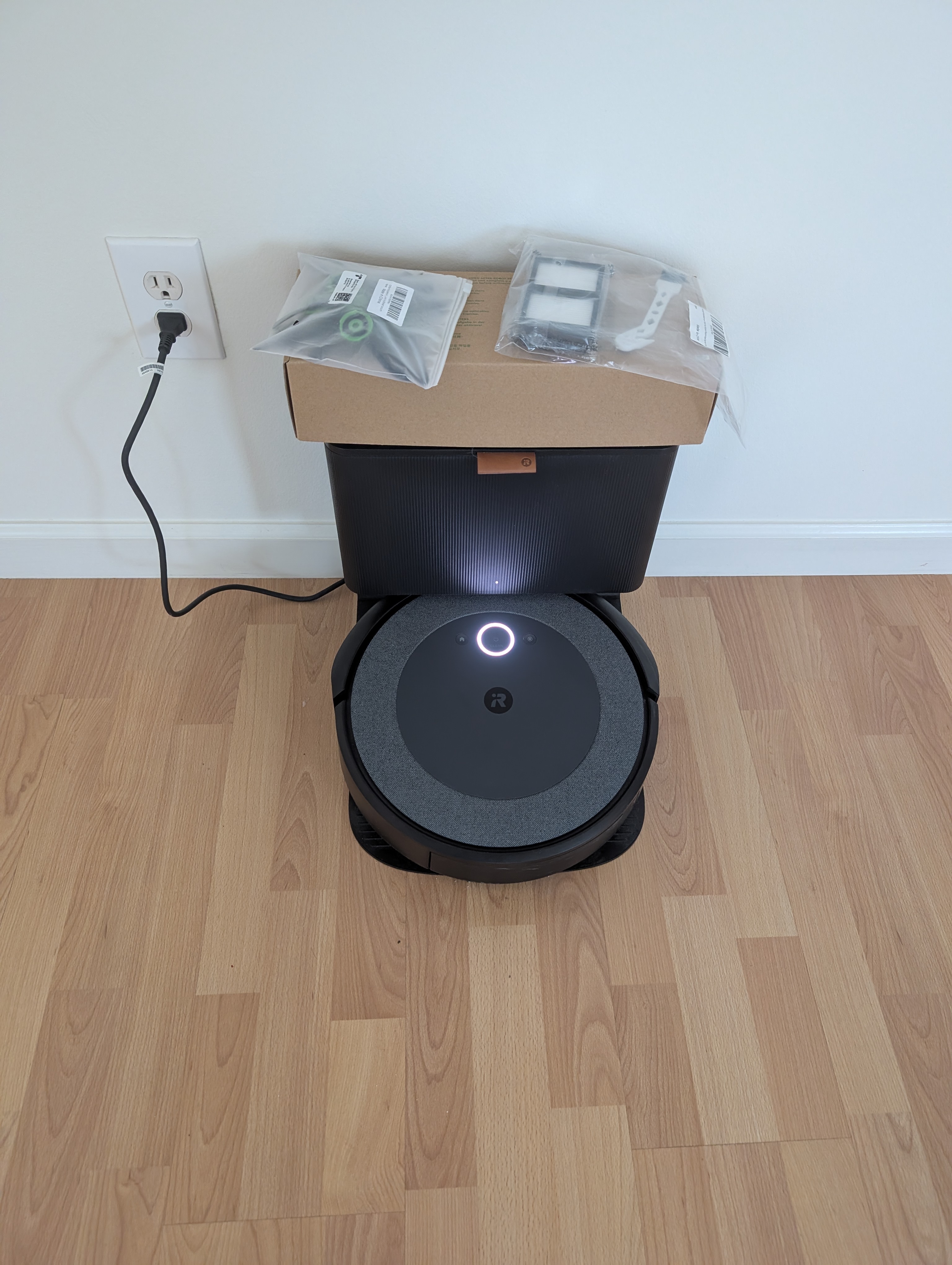 Reassembled Roomba i5 charging on its dock with new filters and bag